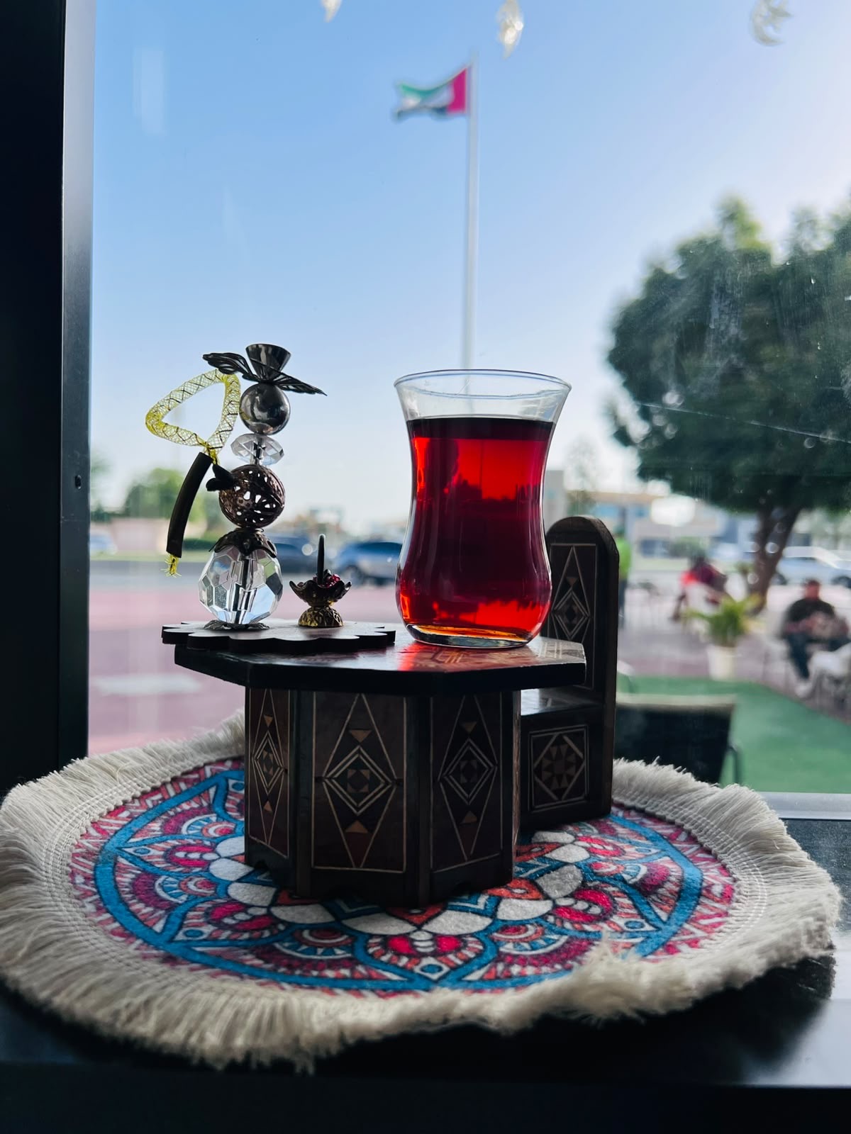 Turkish glass of red tea by the window with a view of the UAE flag