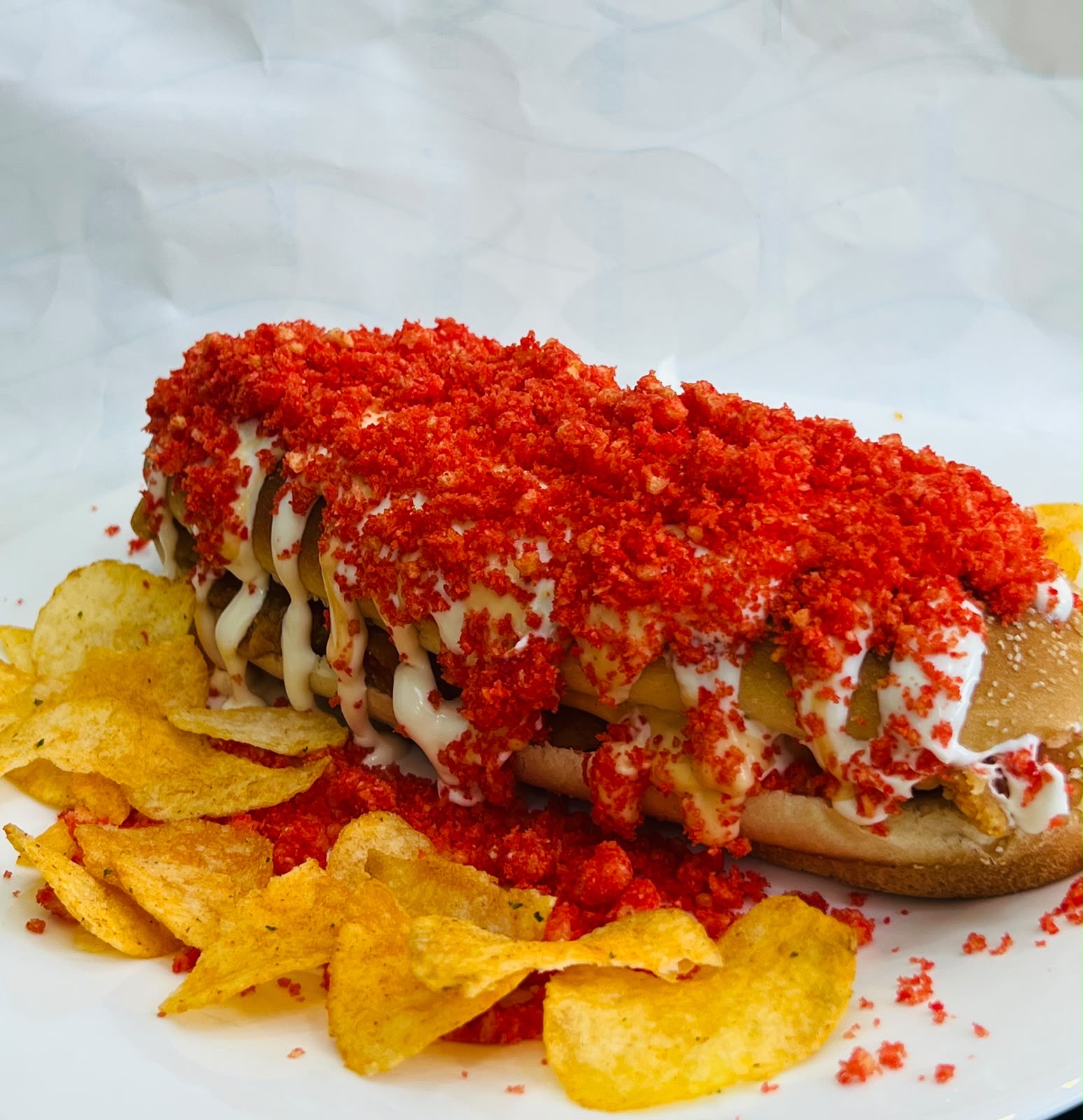 Emarati Combo — loaded sandwich with mayo drizzle and crushed red topping, served with chips